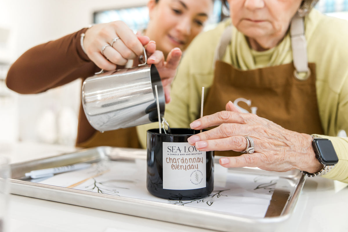 Staff helping a guest pour a candle at the Sea Love candle bar